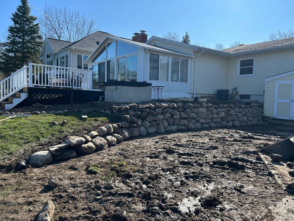 Boulder retaining wall and stone steps behind sunroom