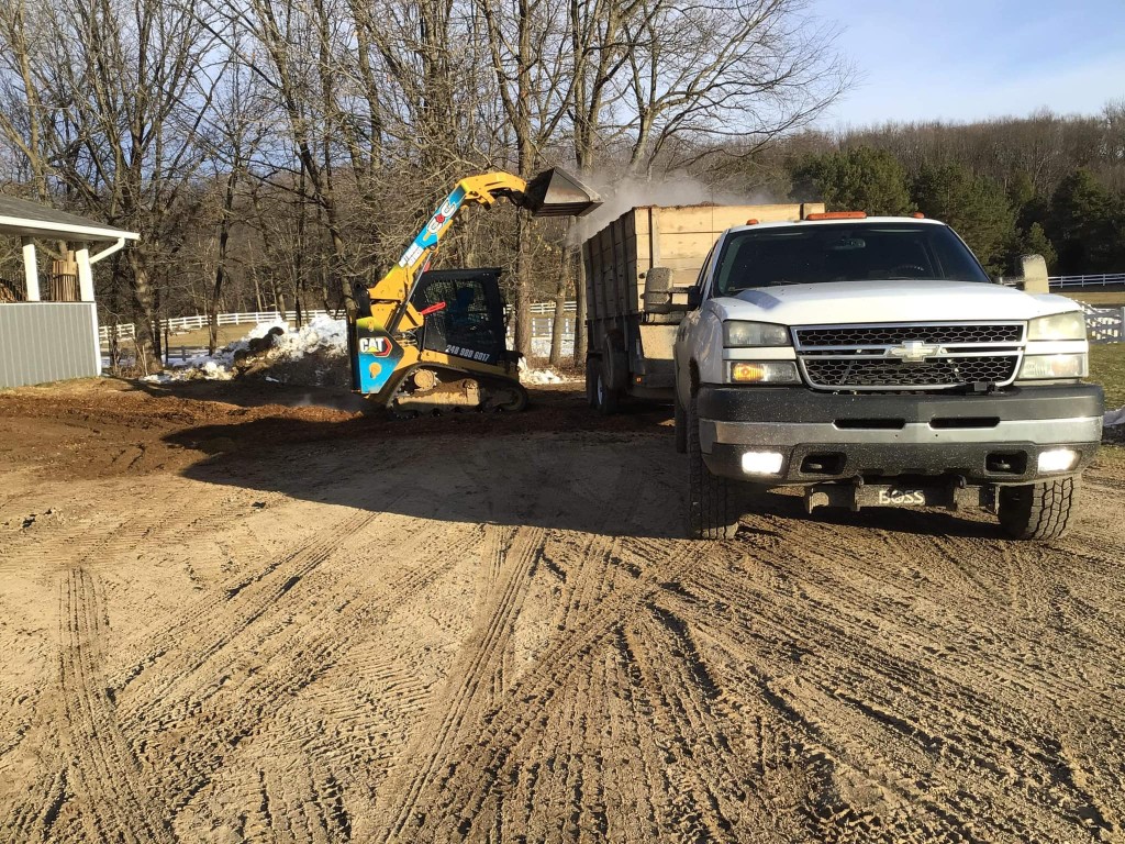 Skid steer and dump truck working on a land clearing and grading project